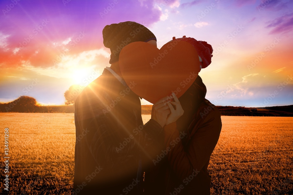 Composite image of happy young couple holding heart shape paper