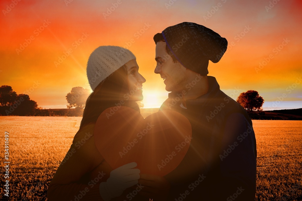 Composite image of happy couple holding paper heart