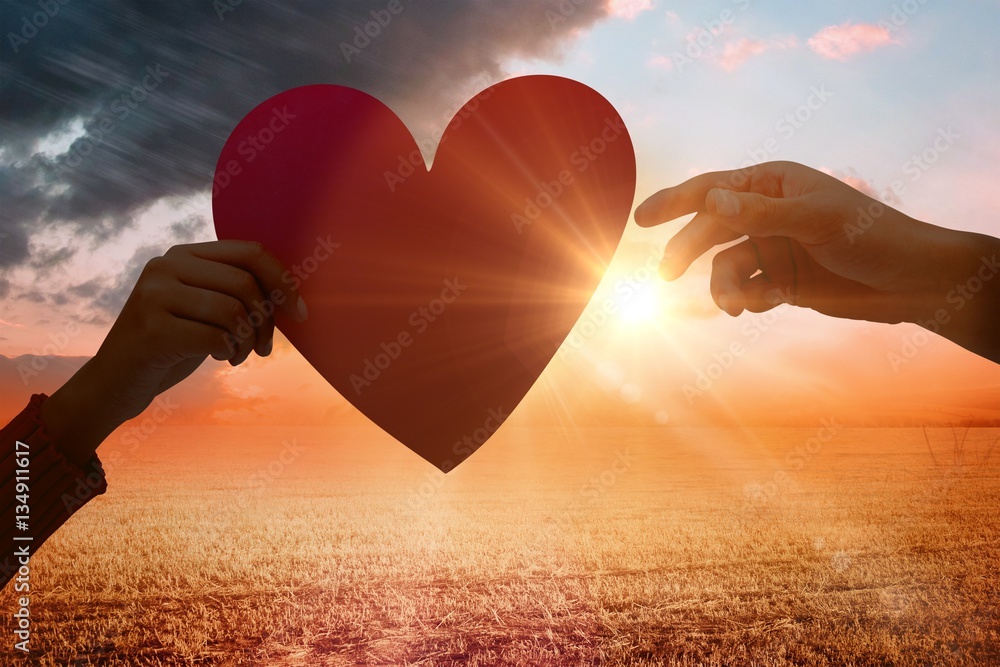 Composite image of couple holding a heart