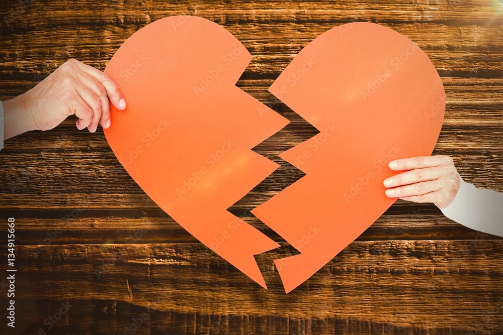 Composite image of couple holding broken heart shape paper