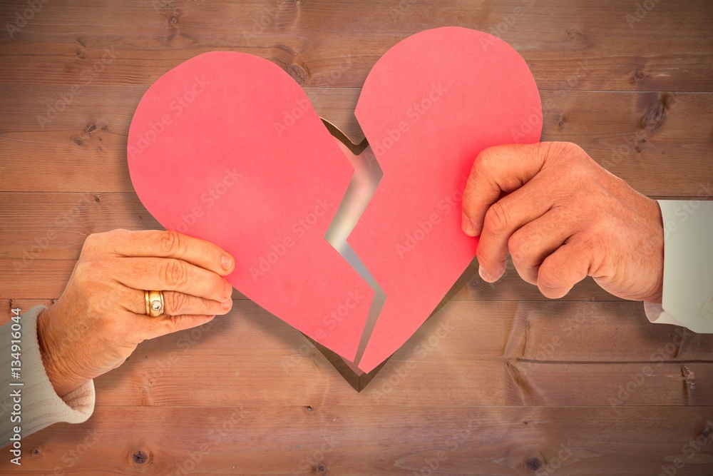 Composite image of couple holding a broken paper heart