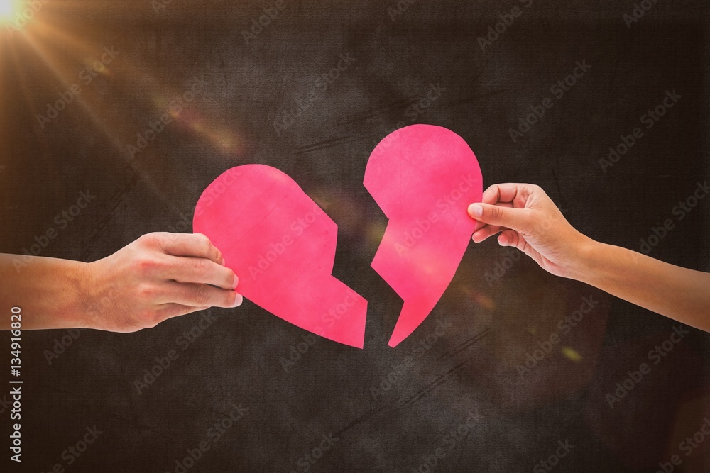 Composite image of hands holding two halves of broken heart