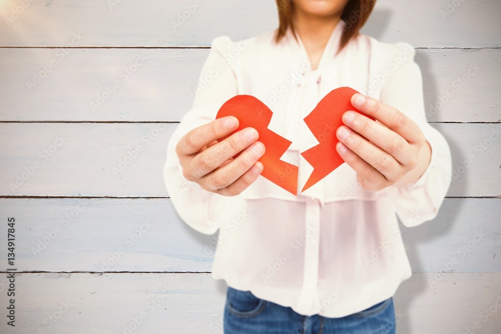 Composite image of woman holding broken heart paper