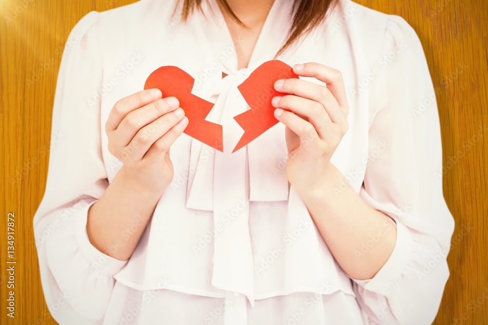 Composite image of woman holding broken heart paper