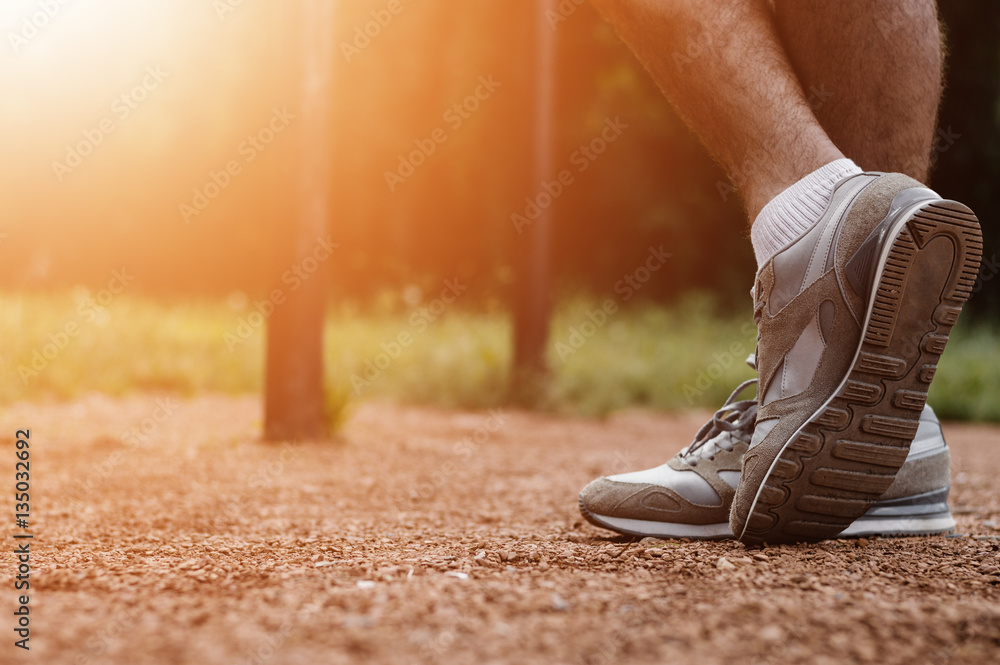 Athletic runner preparing for morning workout in the park, lens