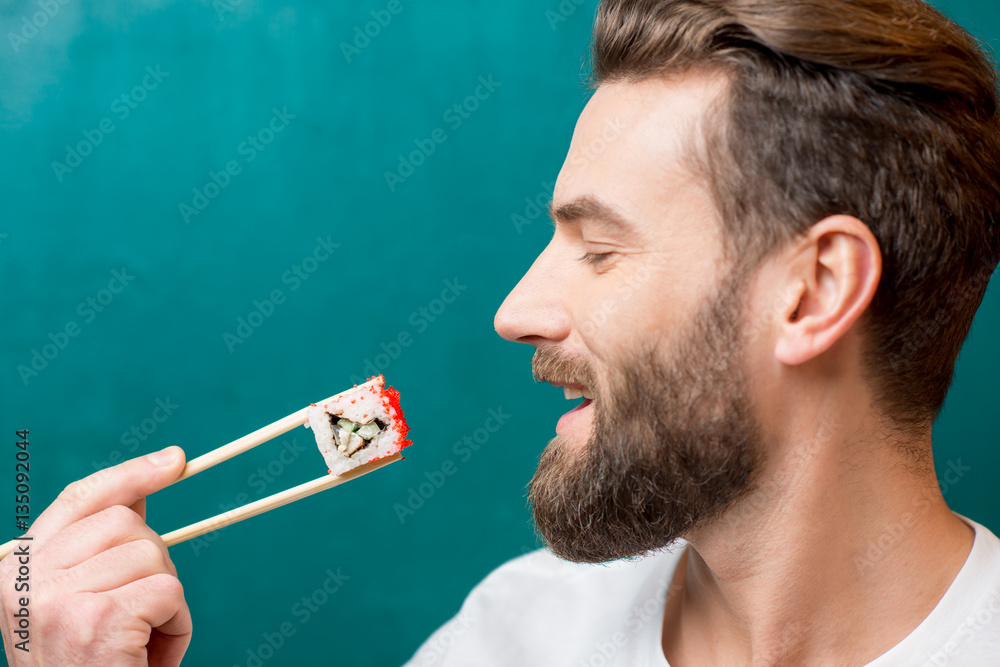 Man eating sushi with chopsticks on the green background