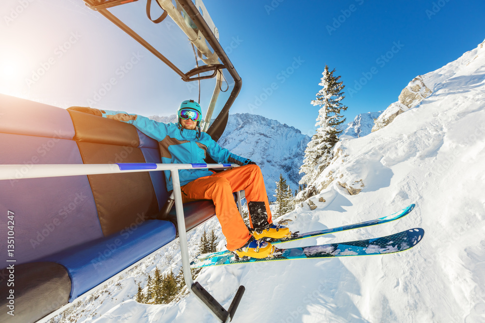 Skier sitting at ski chair lift in Alpine mountains