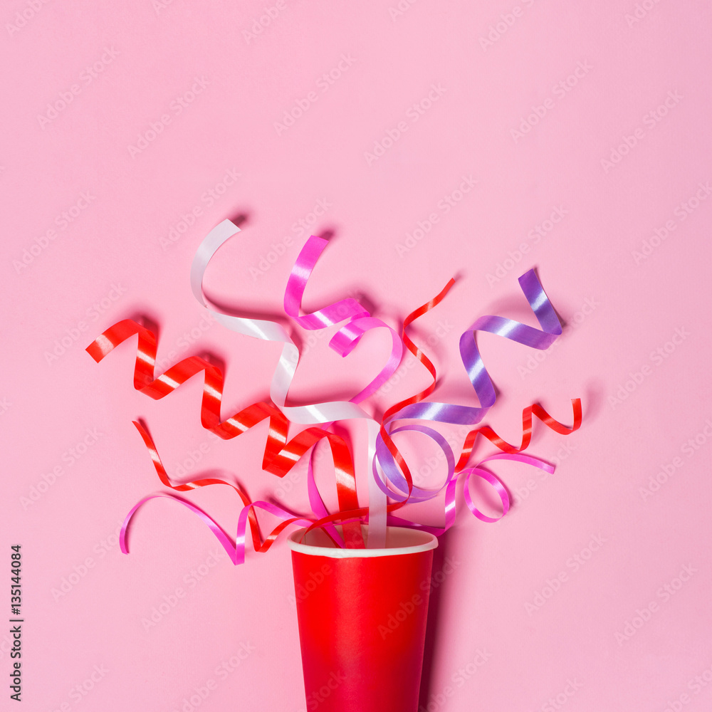 Flat lay of Celebration. Paper cup with colorful party streamers