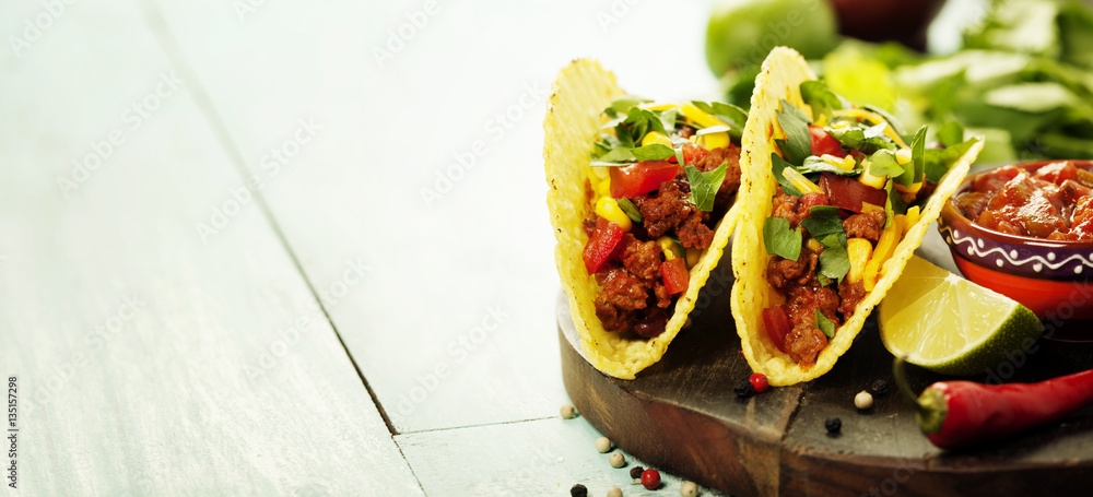 Mexican nachos chips and tacos with meat, beans and salsa