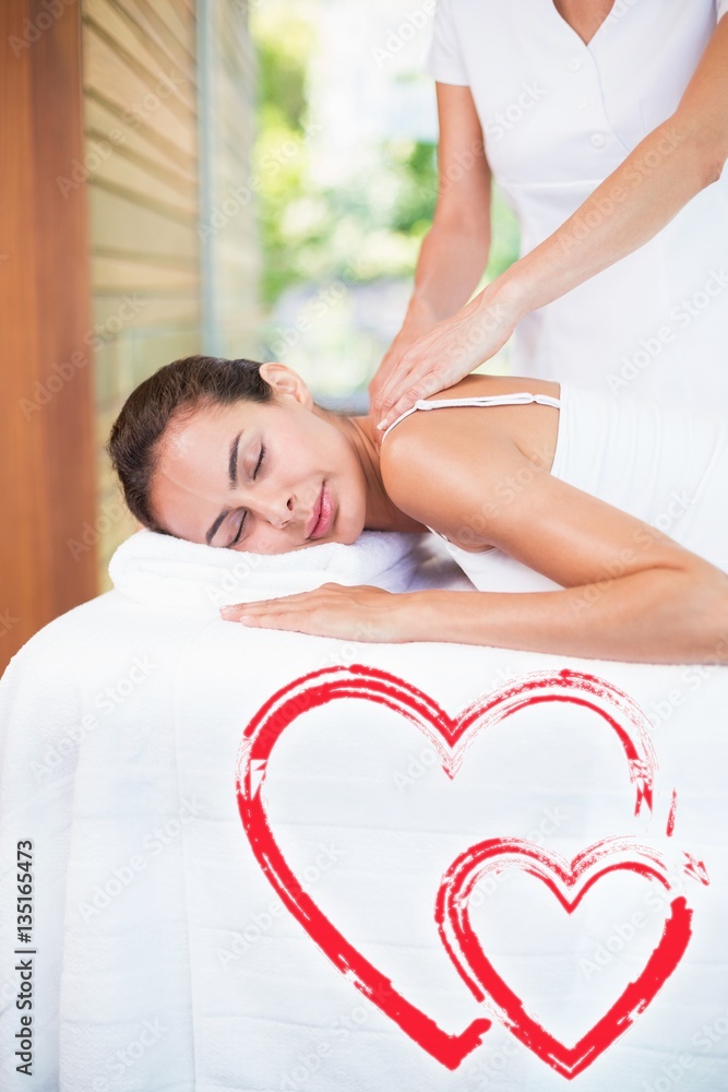 Composite image of pwoman receiving a massage love hearts