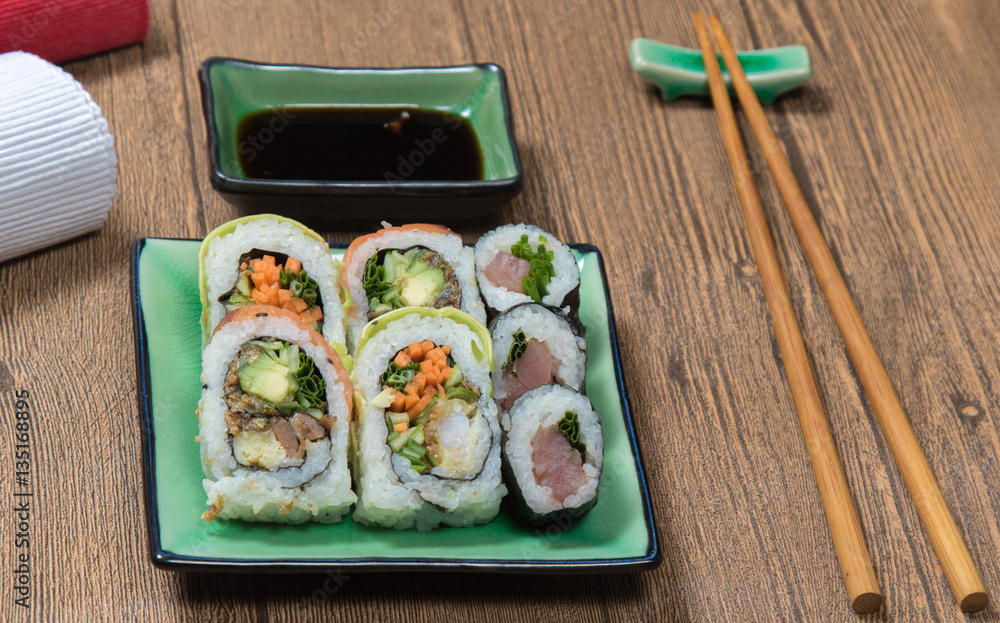 Sushi Set rolls with salmon served on green plate on wooden table