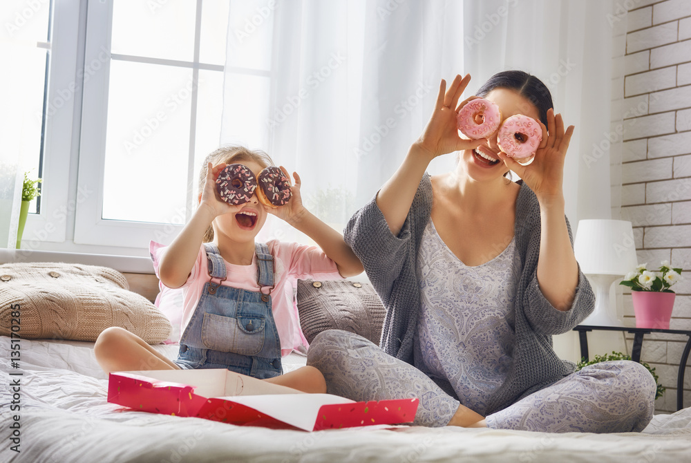 Mother and her daughter eating donuts