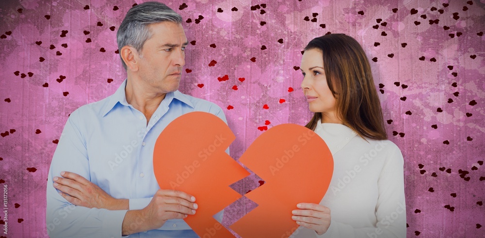 Composite image of couple holding broken heart shape paper