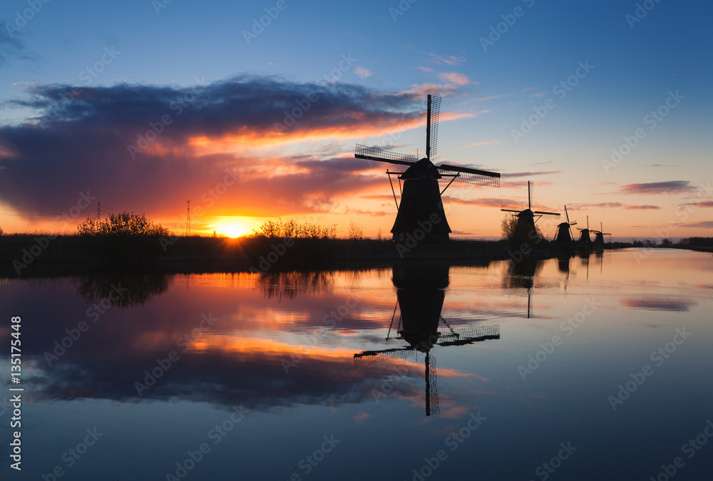 Landscape with beautiful traditional dutch windmills near the water canals with blue sky and clouds 