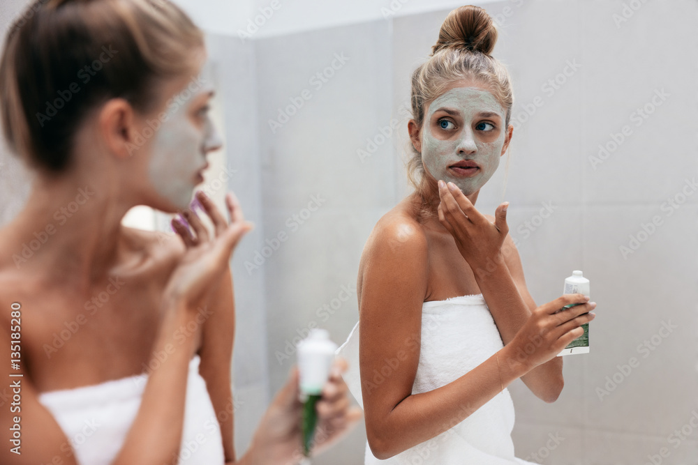 Woman applying mask cream on face in bathroom