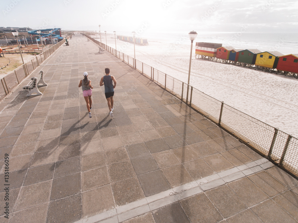 Young couple on morning run at beach promenade