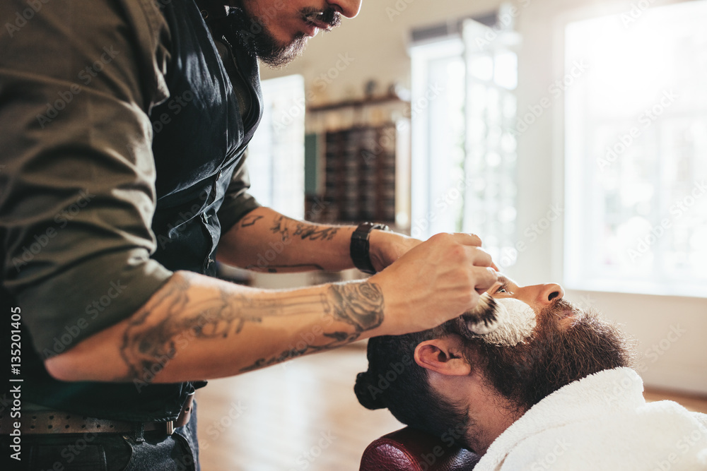 Barber shaving customer in salon