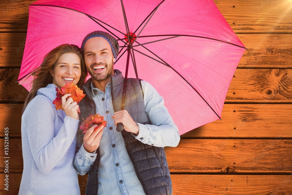 Composite image of happy young couple holding umbrella