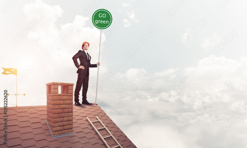 Businessman in suit on house top with ecology concept signboard.