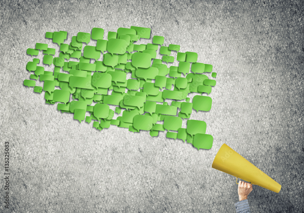 Hand of woman holding green paper trumpet and speech cloud coming out