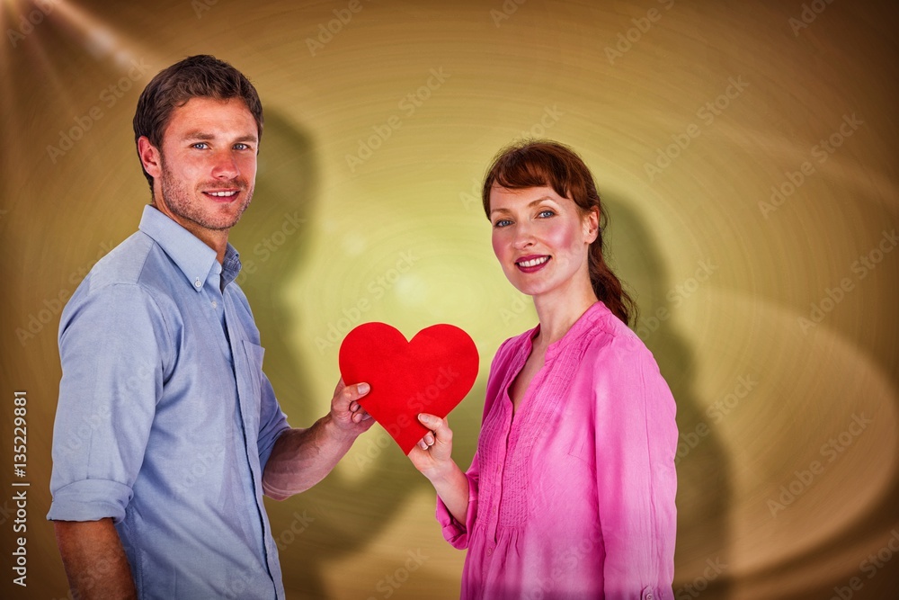 Composite image of couple holding a red heart