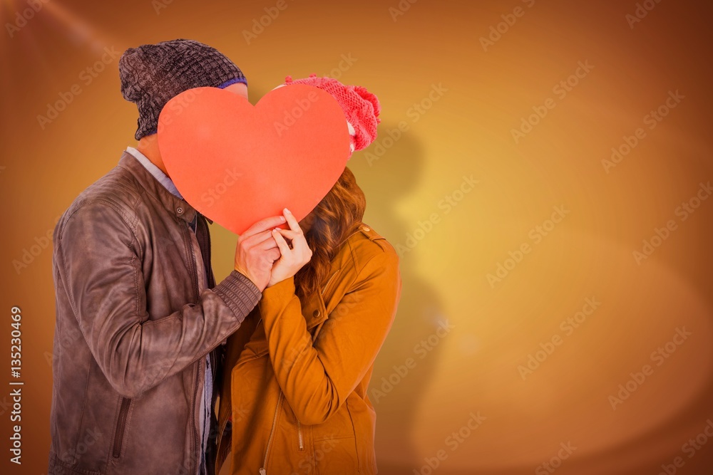 Composite image of happy young couple holding heart shape paper