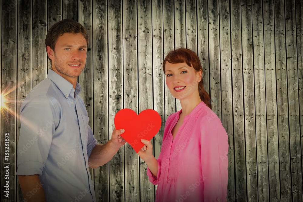 Composite image of couple holding a red heart