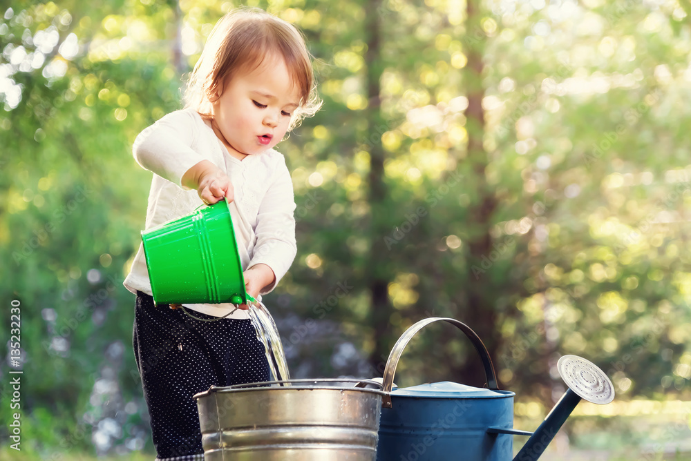 Happy toddler girl playing with watering cans