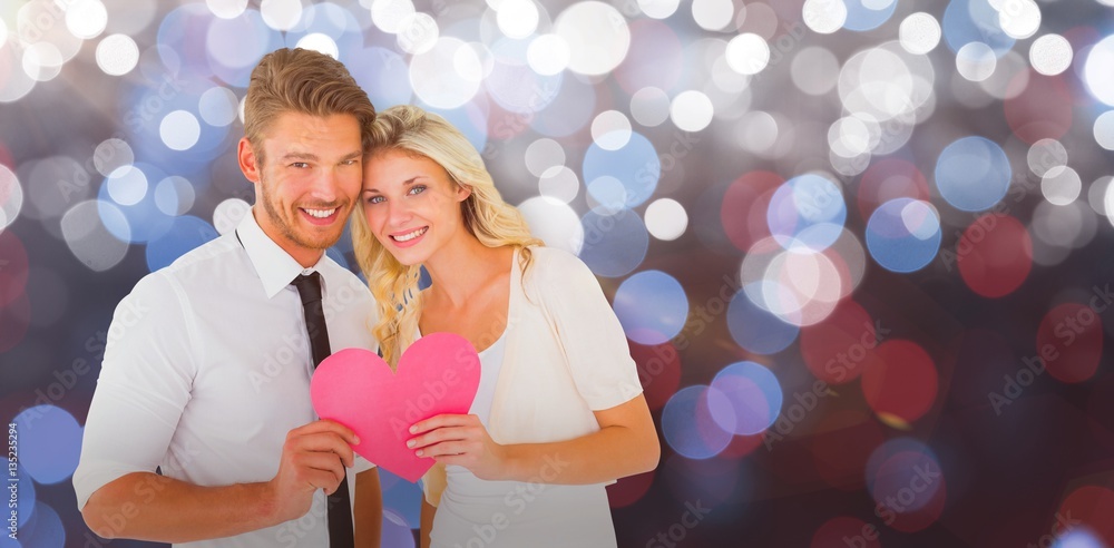 Composite image of attractive young couple holding pink heart