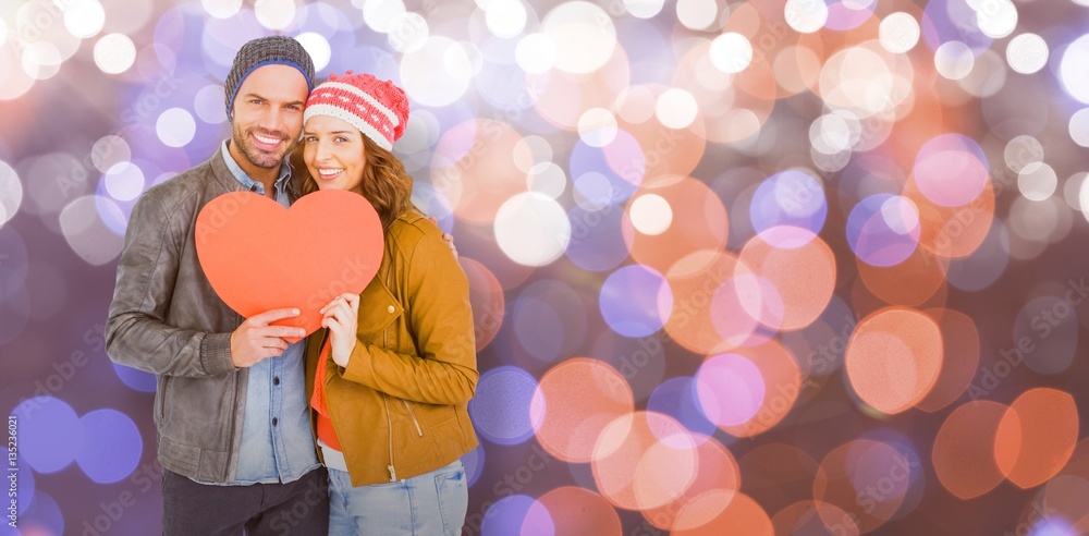 Composite image of young couple holding heart shape paper