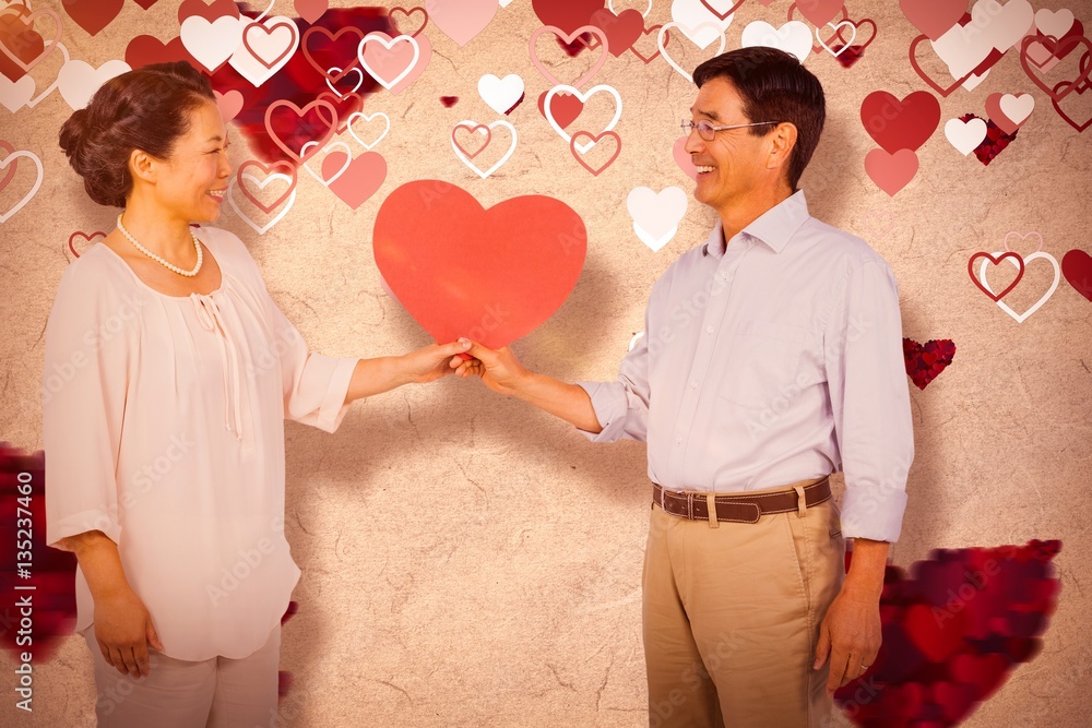 Composite image of older asian couple holding heart