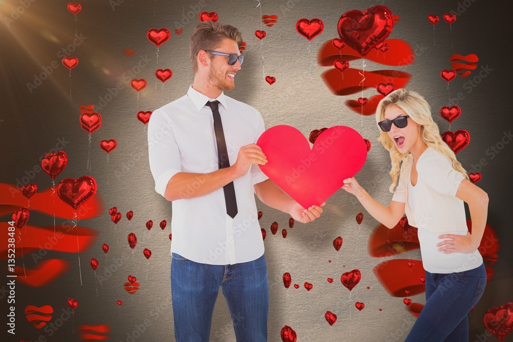 Composite image of cool young couple holding red heart