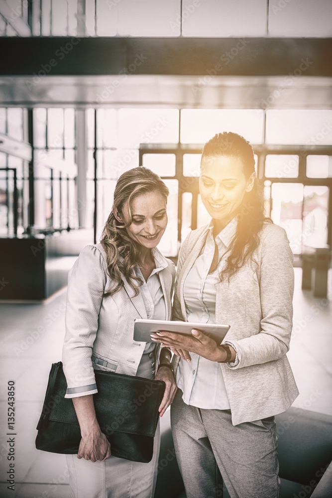 Businesswoman showing digital tablet to colleague