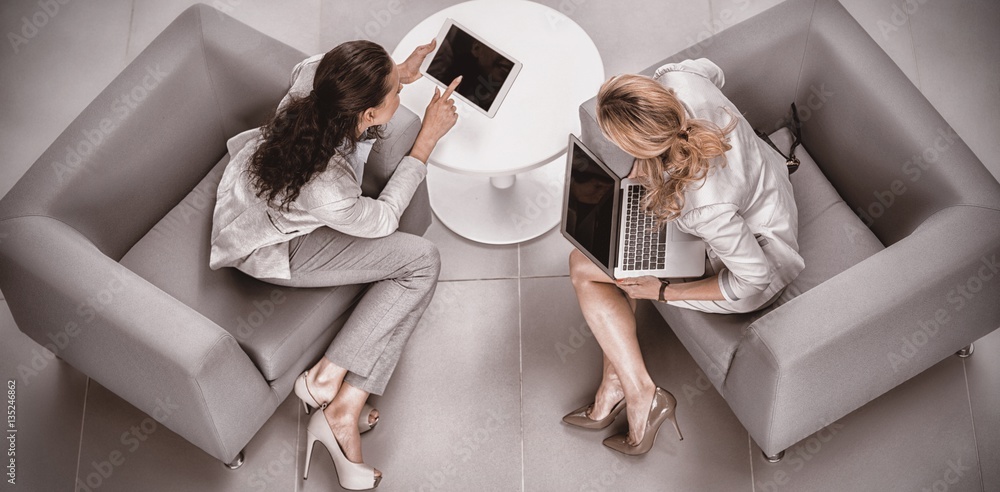 High angle view of businesswomen discussing over digital tablet 