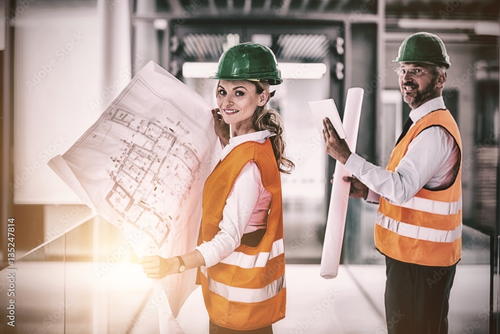 Architects standing with blueprint in office corridor