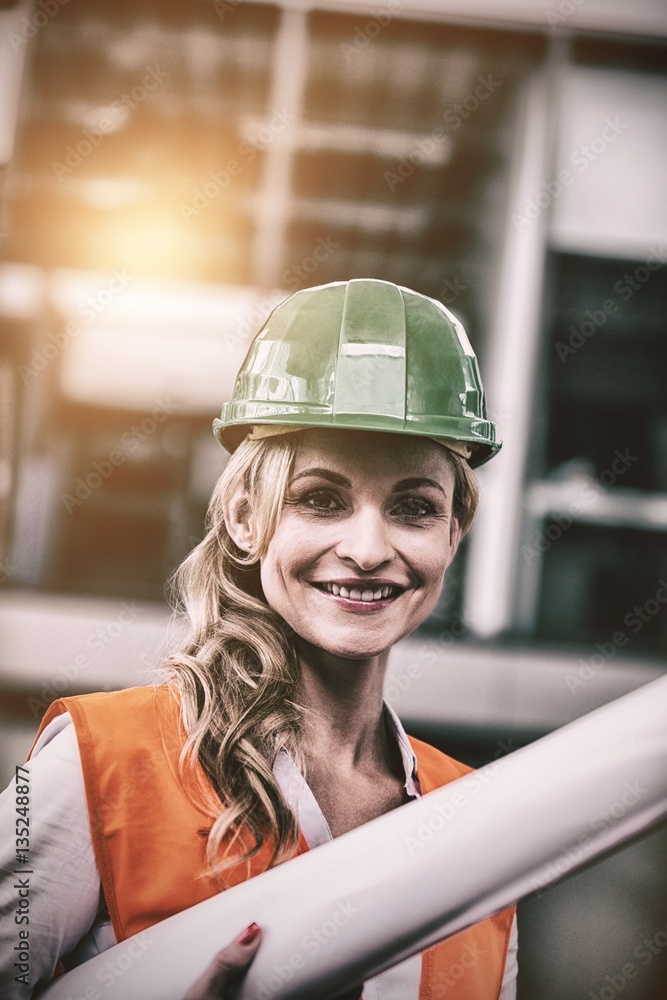 Portrait of architect woman in hardhat holding blueprints