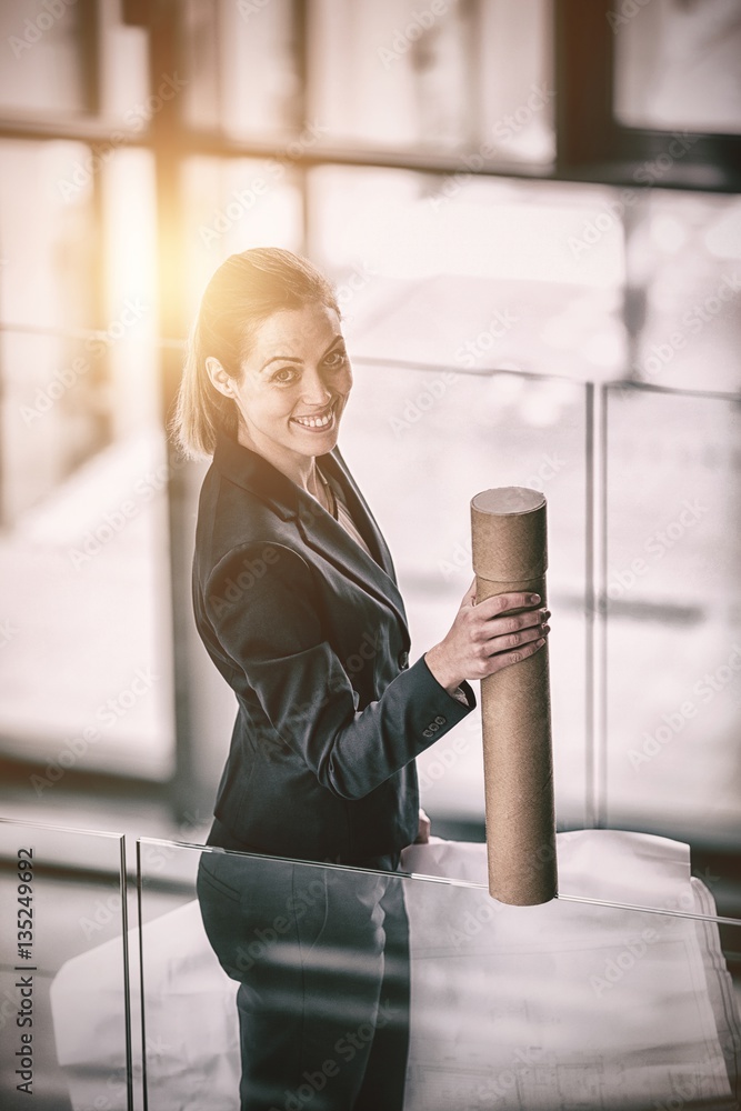 Businesswoman standing at office corridor with chart holder 