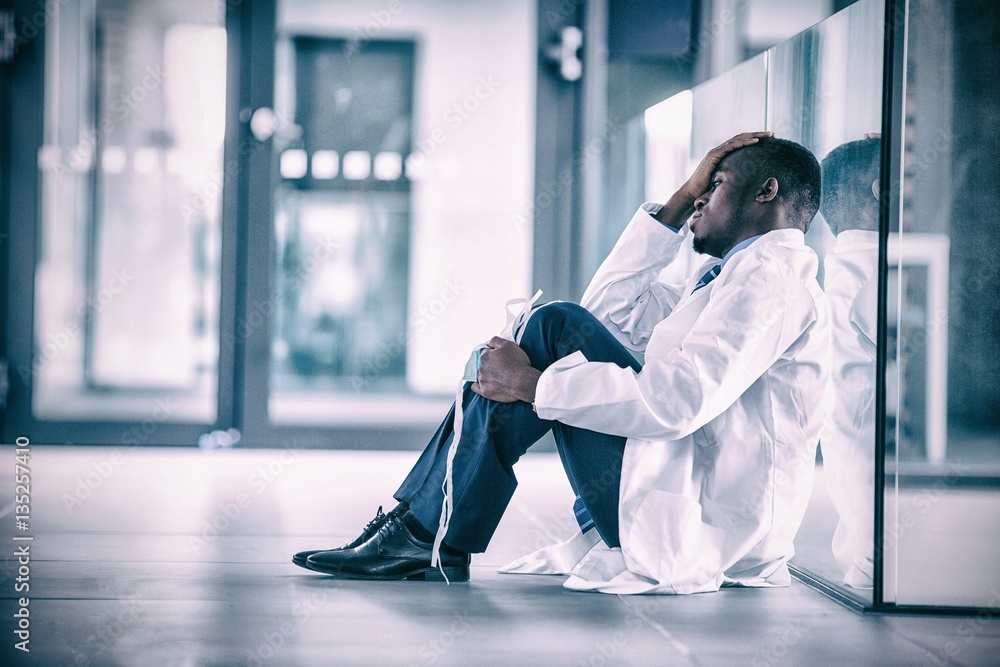 Worried doctor sitting floor