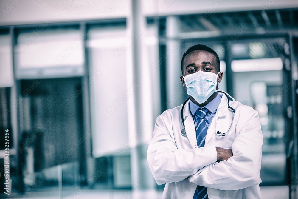 Doctor wearing surgical mask standing with hands crossed