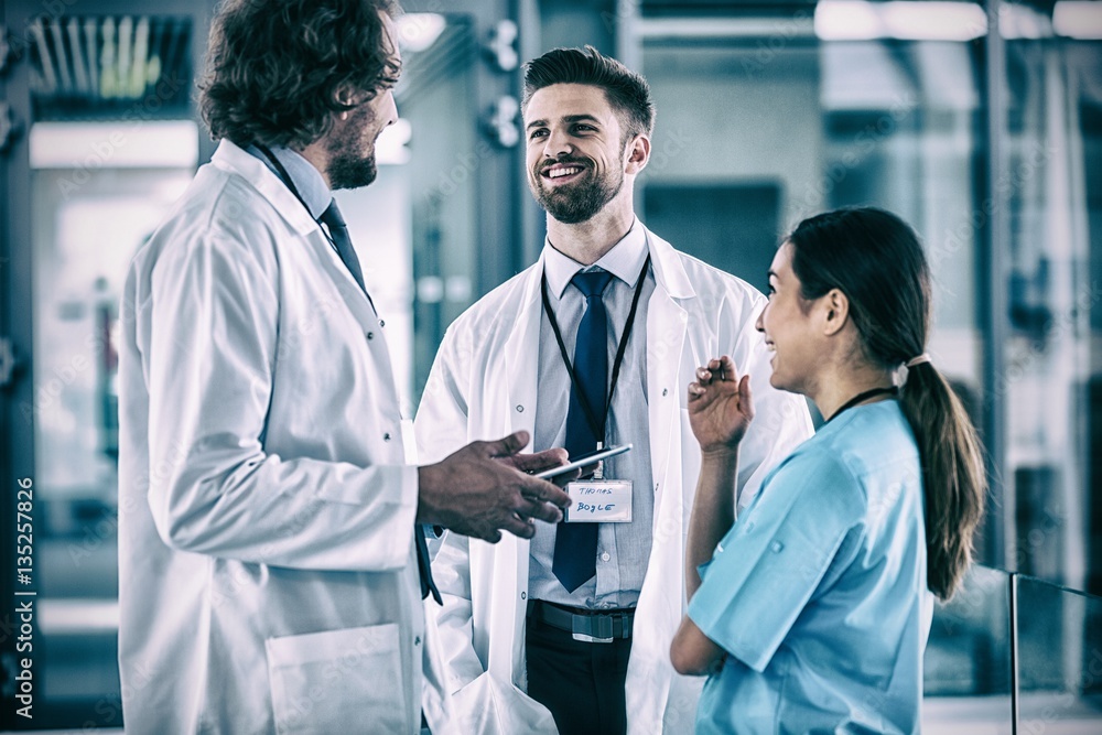 Doctor holding digital tablet having discussion with colleagues