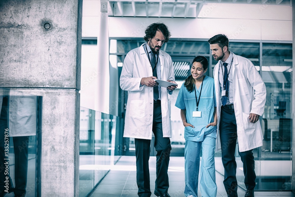 Doctor holding digital tablet having discussion with colleagues