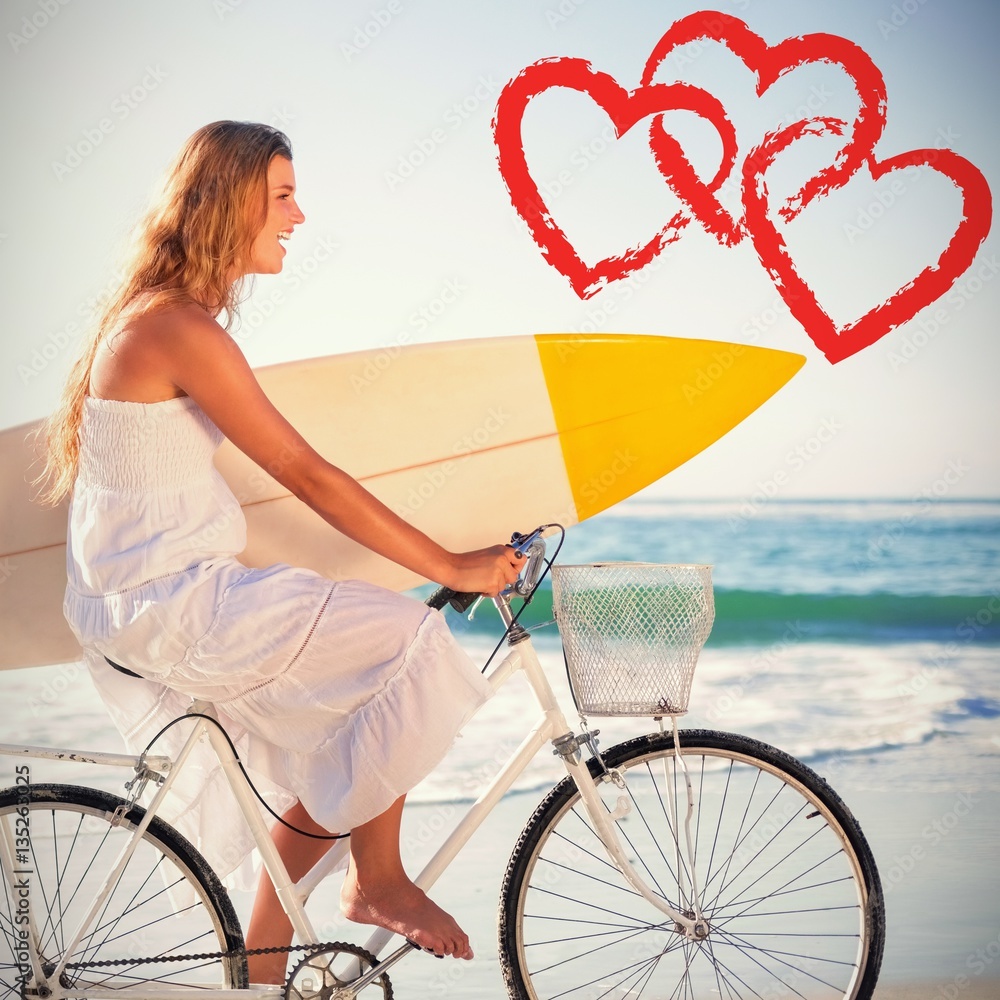 beautiful surfer in sundress on bike holding surfboard at beach