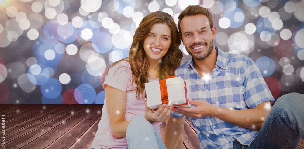 Composite image of happy young couple holding gift