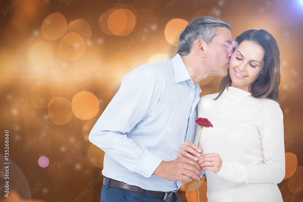 Composite image of husband kissing wife while holding rose