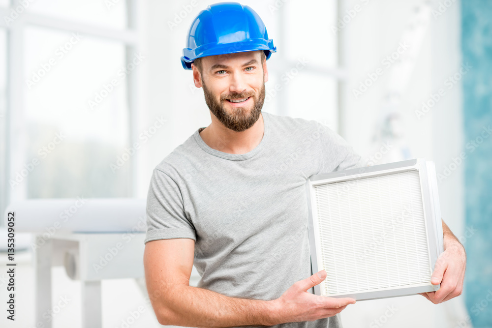 Worker holding air filter for installing in the house ventilation system. Purity of the air concept