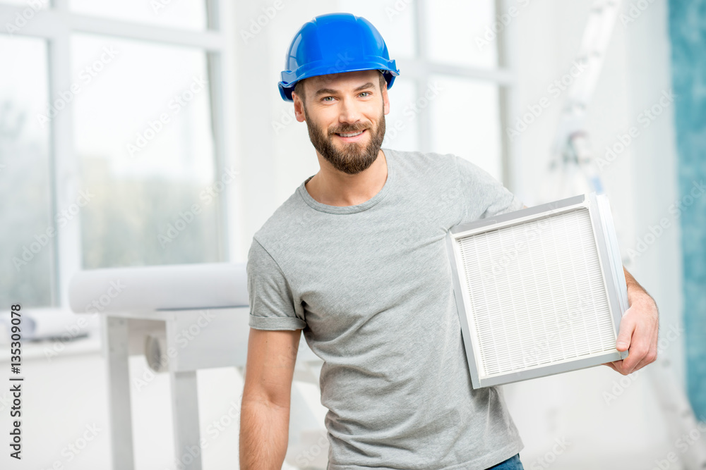 Worker holding air filter for installing in the house ventilation system. Purity of the air concept