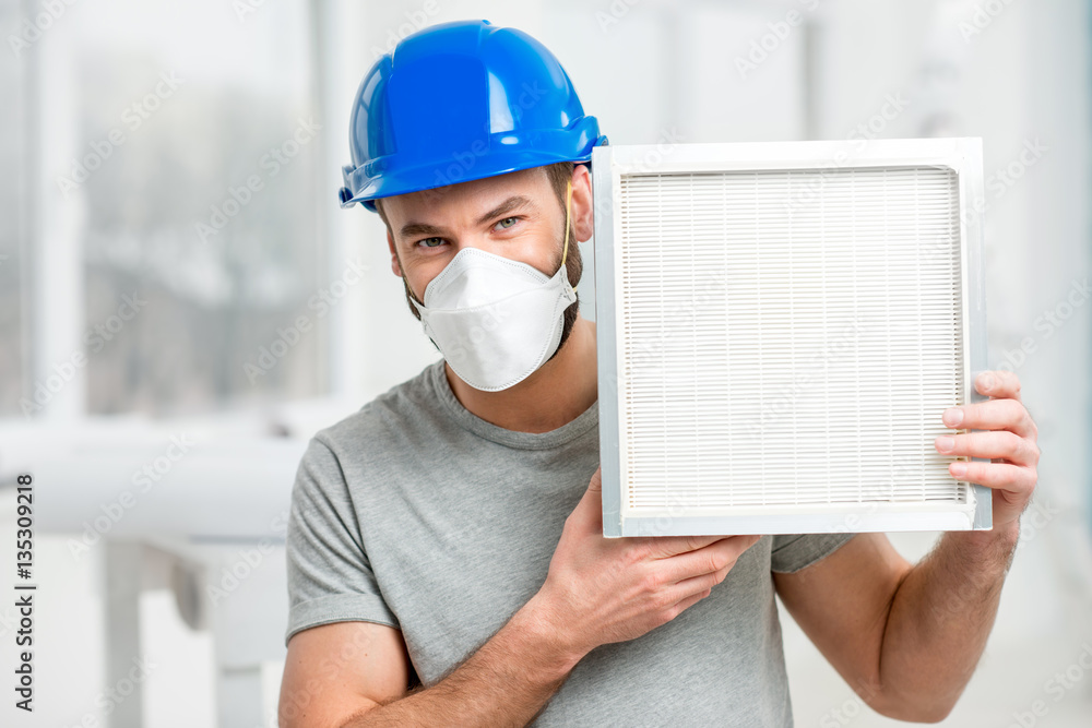 Worker holding air filter for installing in the house ventilation system. Purity of the air concept