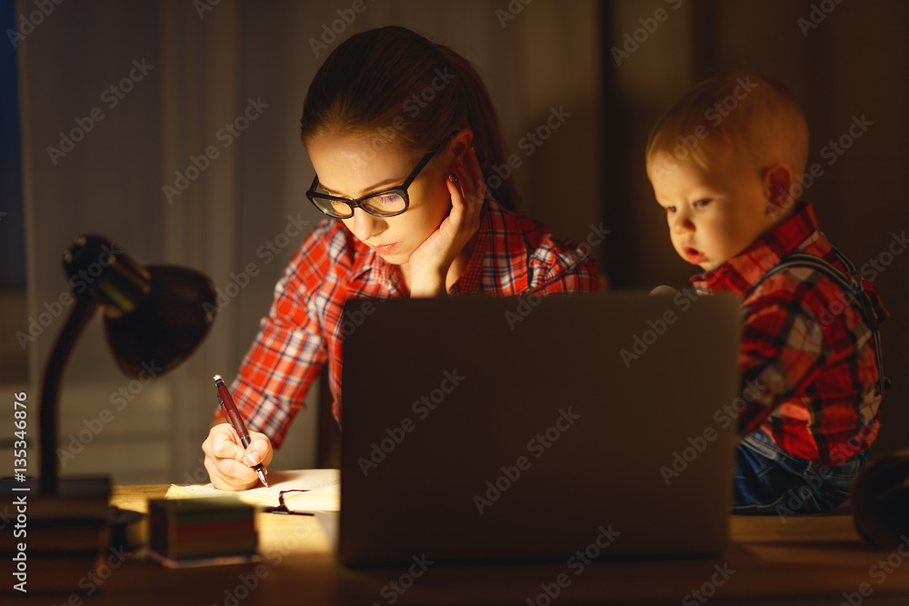 woman mother working  with a baby at home behind a computer