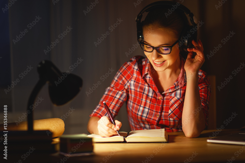 young woman student in headphones working on the computer at nig