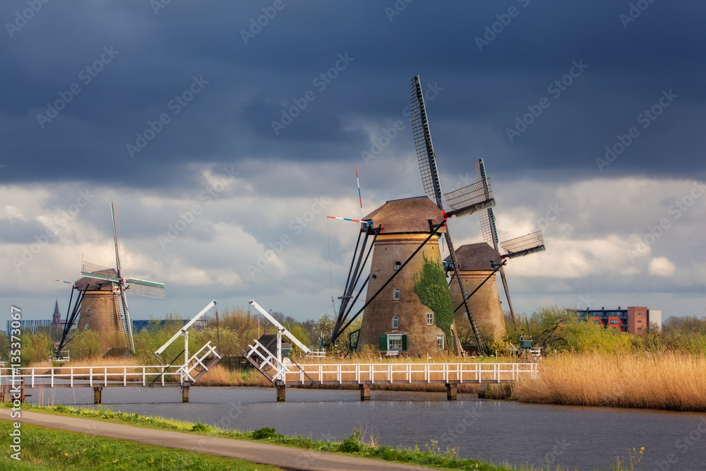 Windmills against cloudy sky at sunset in famous Kinderdijk, Netherlands. Rustic landscape with trad